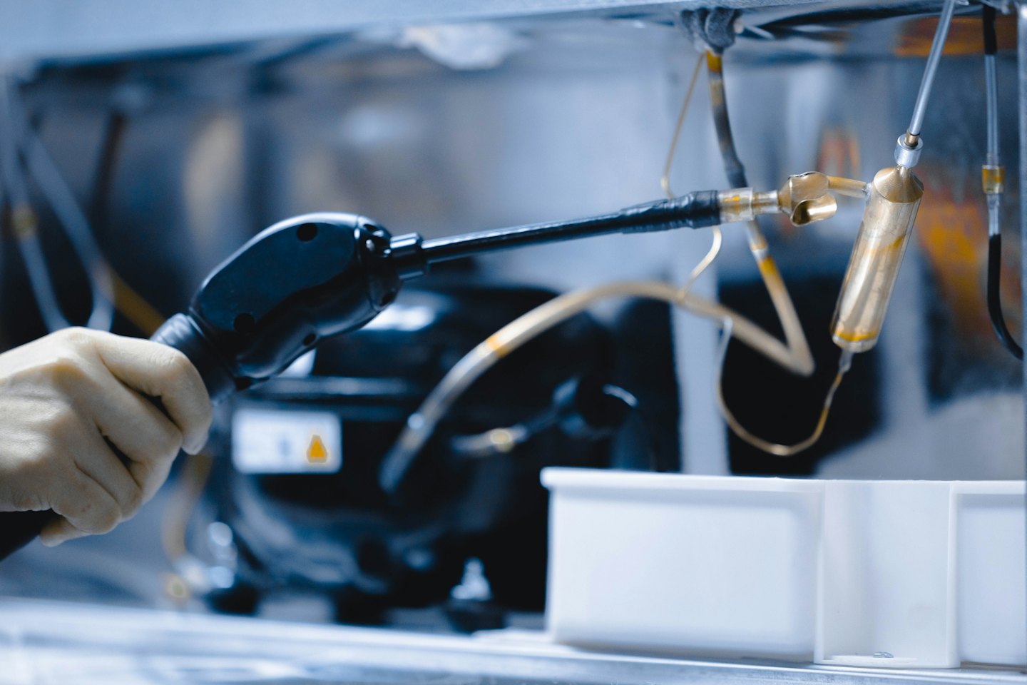 Technician repairs refrigeration unit with specialized tools.